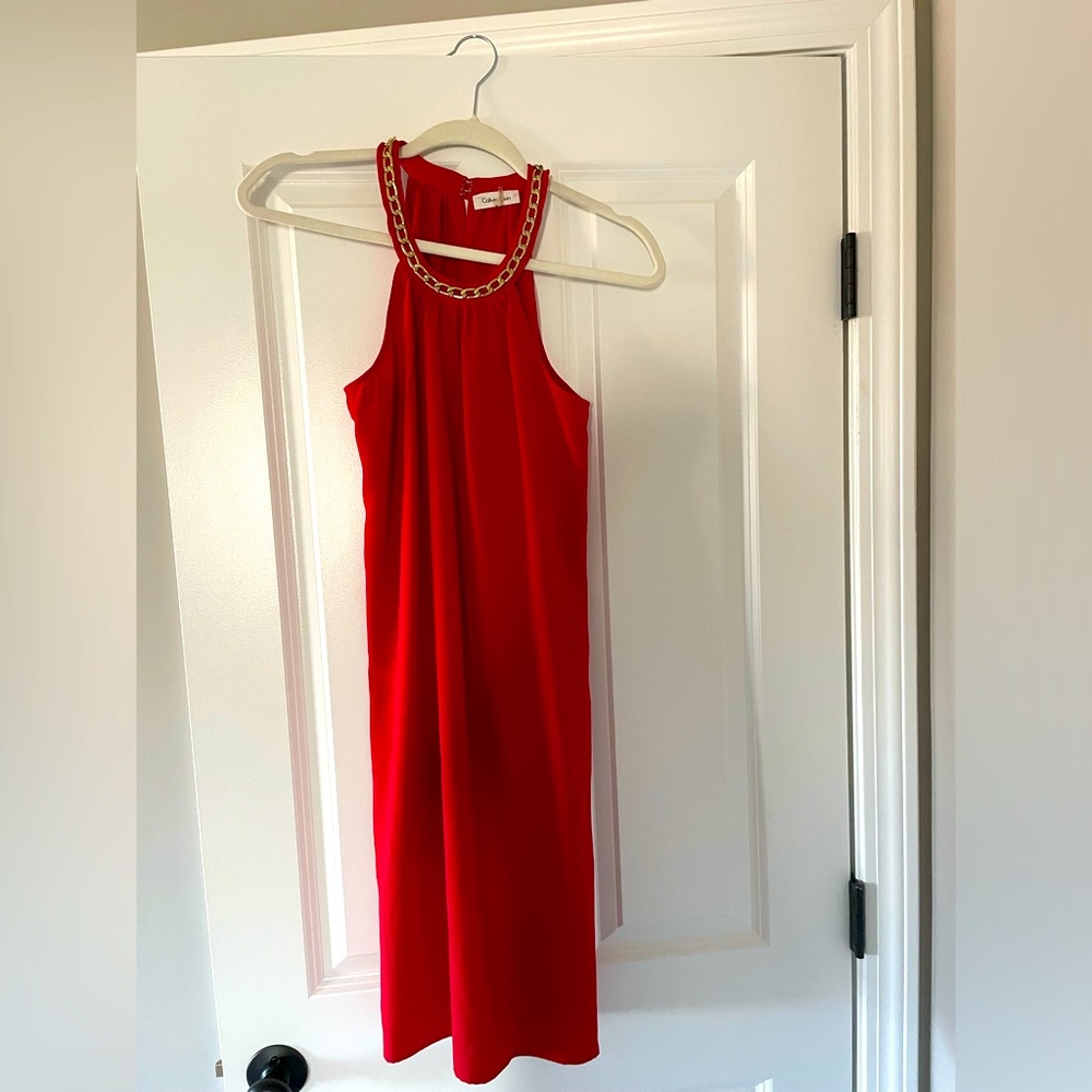 Red halter dress with gold chain around neckline.